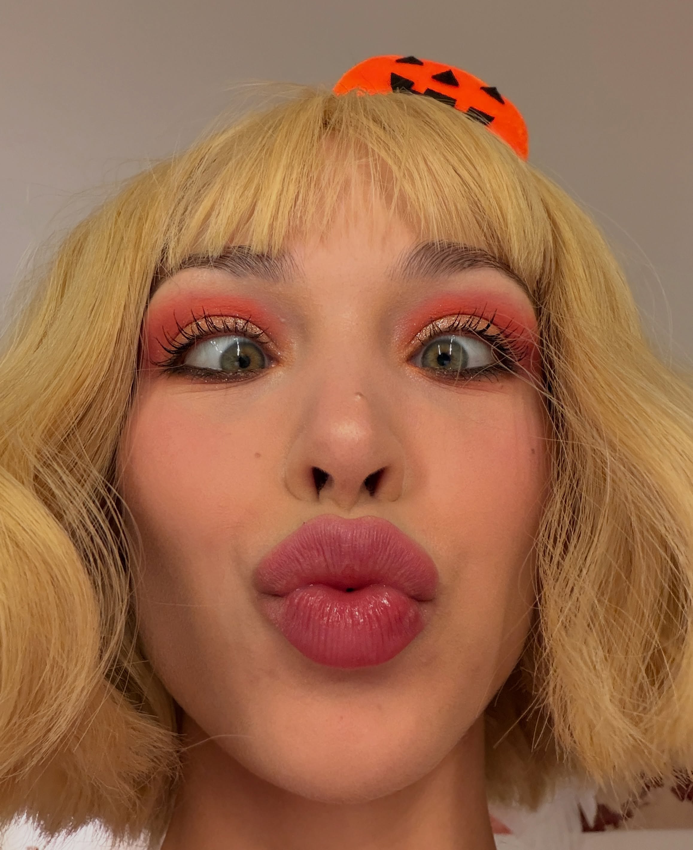 Close-up of Eva Purr pouting with coral eyeshadow and a pumpkin headband